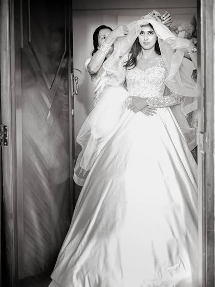 A black and white shot of the bride getting her veil adjusted, framed in a doorway for a classic, documentary feel.