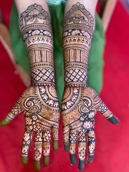 This design is filled with auspicious symbols, including elephants, paisleys, and lotus flowers, creating a dense and traditional bridal look.
