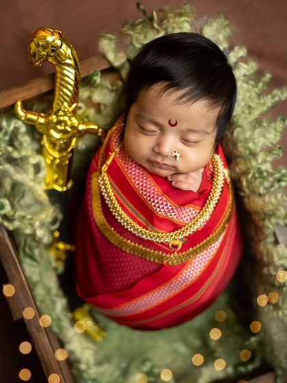A high-angle shot of the baby in the wooden crate, with bokeh lights adding a magical, celebratory sparkle to the scene.