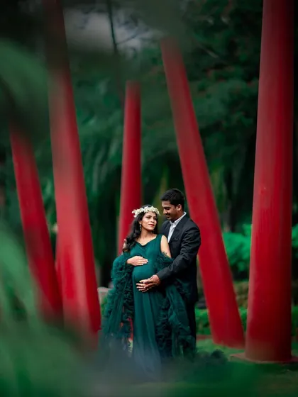 A striking couple's portrait set against a modern art installation. The contrast of the red pillars and green foliage makes this photo pop.
