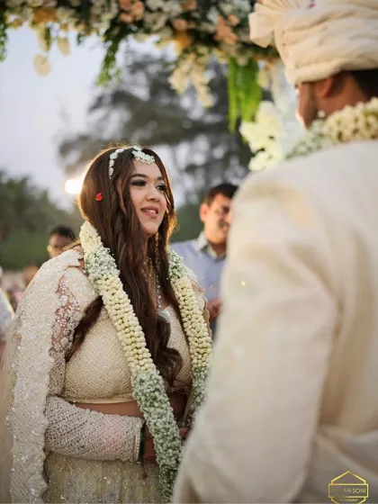 A close-up of the bride during the varmala ceremony. Her makeup is subtle and elegant, allowing her joyful expression to be the focus.