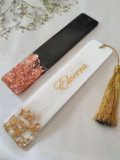 My personalized bookmarks are perfect for any book lover. This set shows two styles: one in black and rose gold, and another in white and gold with a custom name.