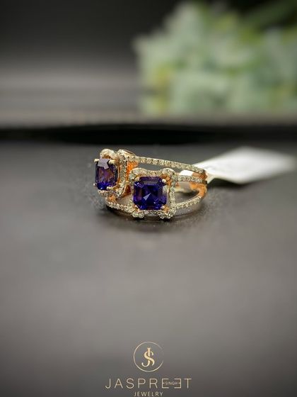This bold ring features two large, square-cut purple gemstones set side-by-side, each framed by a halo of brilliant diamonds. The split shank band is also diamond-studded, ensuring sparkle from every possible angle.