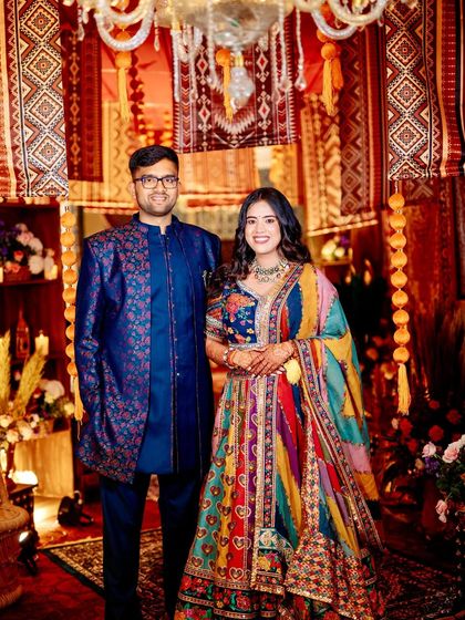 The couple, dressed in vibrant, multi-colored outfits, perfectly complementing the rich and eclectic vintage bazaar theme of their event.