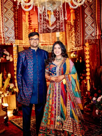 The couple, dressed in vibrant, multi-colored outfits, perfectly complementing the rich and eclectic vintage bazaar theme of their event.