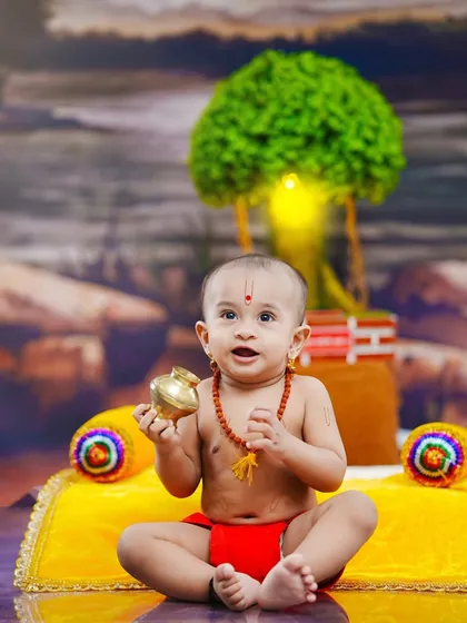 Holding a small brass 'lota', this little devotee looks up with a curious and happy expression.
