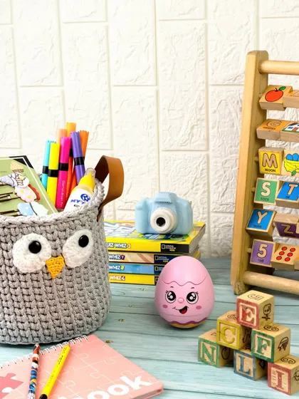 How cute are these? A hand-crocheted owl basket is styled as a fun and practical storage solution for a child's desk, filled with pens, toys, and books.