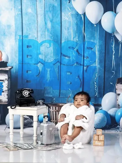A newborn version of the Boss Baby theme, with the baby wrapped in a white robe in a tiny armchair.