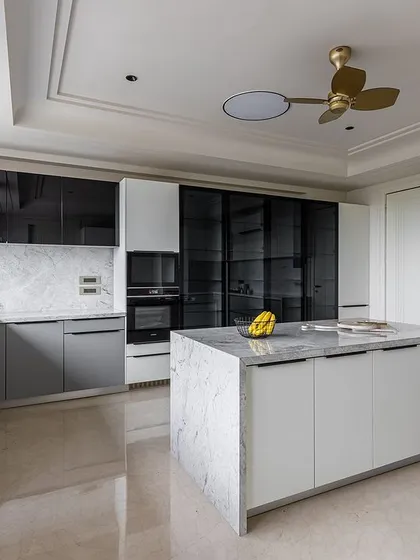 This view showcases the combination of solid, glass, and open-front cabinets, providing a mix of concealed storage and display space. The island is topped with a waterfall granite counter.