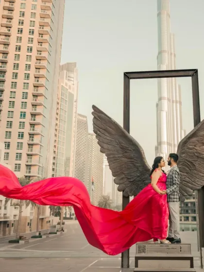 An iconic shot with the angel wings sculpture in Dubai. The flowing pink trail of the gown gives the bride her own set of wings for a truly magical pre-wedding picture.