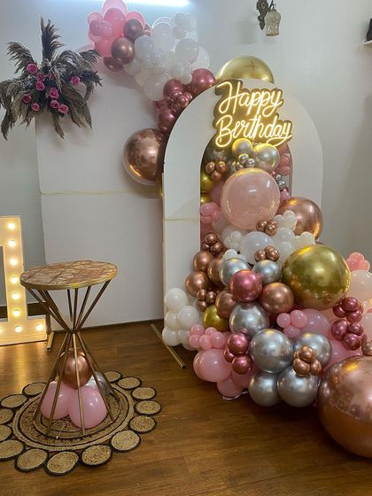 This is a duplicate of ID 22, 69, 160, 214, 234. A stylish and modern first birthday decoration for a home party. This setup features a balloon cascade in rose gold, pink, and white, a 'Happy Birthday' neon sign, and large marquee letters.