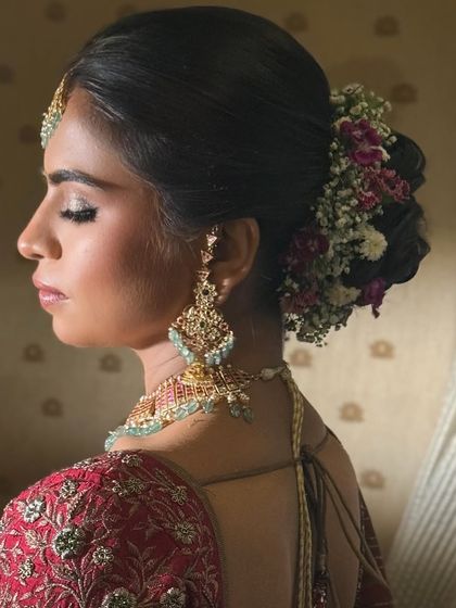 A close-up of the bride's serene expression, her floral bun adding to the overall elegance of her bridal look.