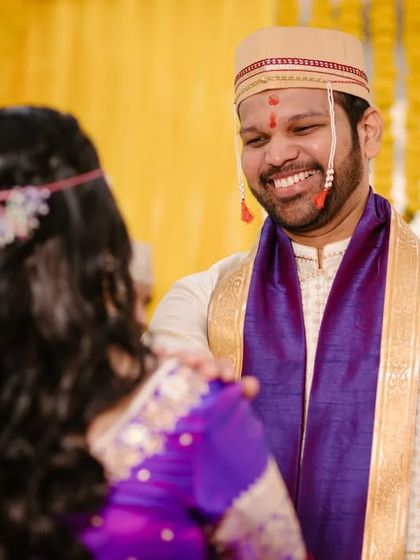 A candid moment showing the groom's happy expression as he looks at his bride during the 'antarpat' ritual.