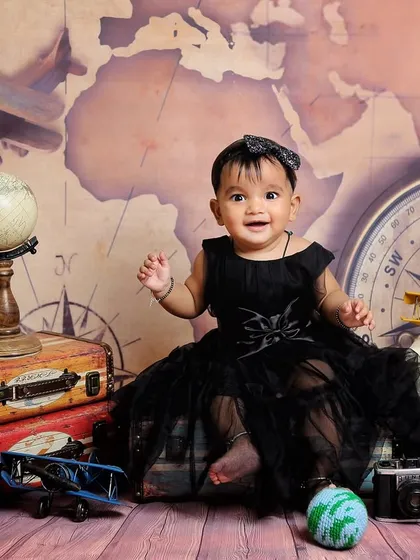 A little world traveler. This sitter session features a vintage travel theme with a world map, old-fashioned suitcases, and toy airplanes.