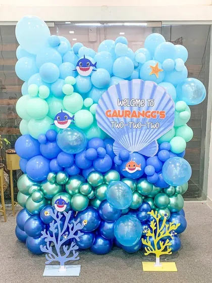 We built this complete Baby Shark themed balloon wall for Gaurangg's 'two-two-two' birthday. The design uses multiple shades of blue and green to create an underwater effect, complete with character cutouts, coral props, and a custom seashell sign.