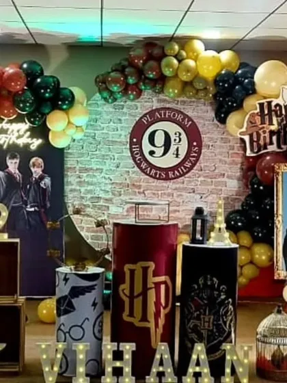Welcome to Hogwarts! This detailed Harry Potter themed birthday party features the iconic Platform 9 3/4 brick backdrop, house color balloon garlands, and themed props like Hedwig, the sorting hat, and character standees.