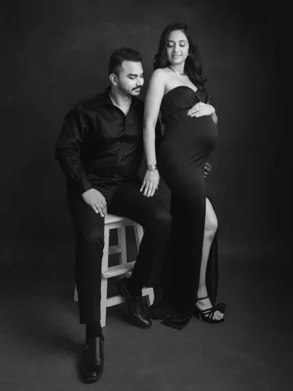 A stylish, full-length monochrome portrait. This pose has a touch of high-fashion elegance, perfect for couples who want a modern and sophisticated maternity shoot.