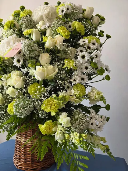 A close-up detail shot of the white and green florals, highlighting the different textures of the roses, daisies, and carnations.