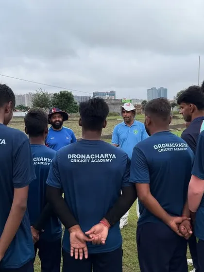 A group of our academy players, wearing the Dronacharya Cricket Academy jersey, listen intently to their coaches. This image captures the spirit of learning and camaraderie that defines our training environment.