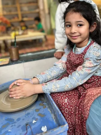 A young girl smiles proudly at her work on the pottery wheel. Her confidence and happiness are what my center is all about.