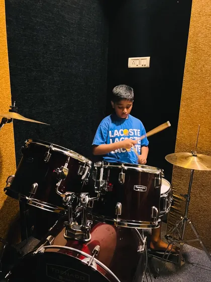 It's never too early to start a big dream. This young student is completely focused during his first drum lessons, learning the fundamentals of rhythm in our soundproofed studio. We nurture passion at every age.