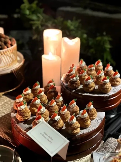 A dessert display of Gajar Halwa in Choux Pastry, set against a backdrop of glowing candles. The warm, ambient lighting creates a cozy and elegant setting for our dessert course.