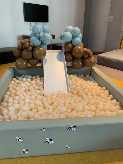 A custom ball pit for the Winnie the Pooh party, decorated with buzzing bees and balloon clusters in brown and blue.