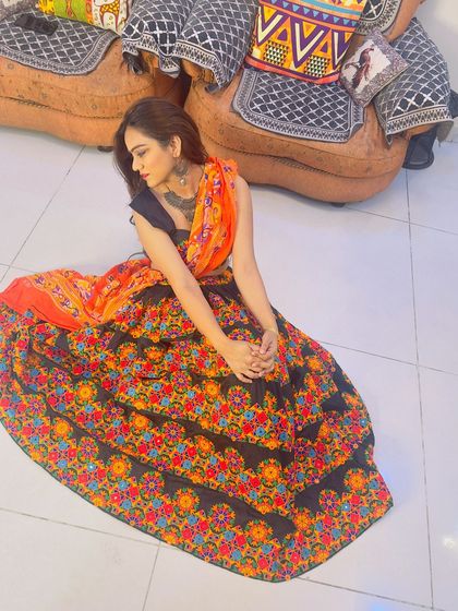 A seated pose showcasing the full flare of the black floral embroidered Garba lehenga.