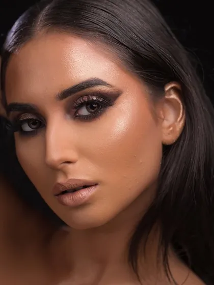 The angle in this shot emphasizes the sharp wing of the eyeshadow and the glowing highlight on the cheekbones.