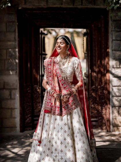 A stunning Gujarati bride in a traditional white and red lehenga, showcasing the beautiful regional diversity we host.