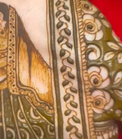 A close-up of a bride's portrait on the palm, showing the wet henna paste before it dries and stains the skin.