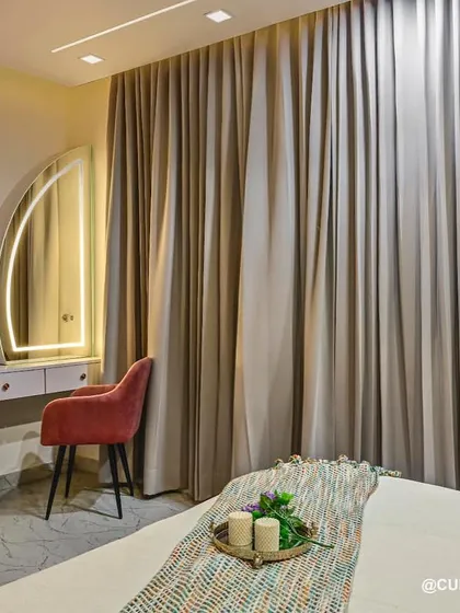This view of the lilac bedroom showcases the custom dressing and TV unit. The arched, back-lit mirror adds a soft, glamorous touch to the vanity area.