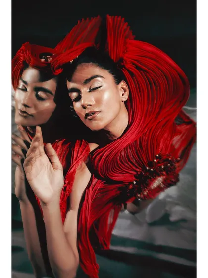 An artistic interpretation using mirrors for the Vaishali S. campaign. The reflection creates a dual perspective on the fluid, ribbon-like texture of the red garment, adding depth and a surreal quality to the fashion portrait.