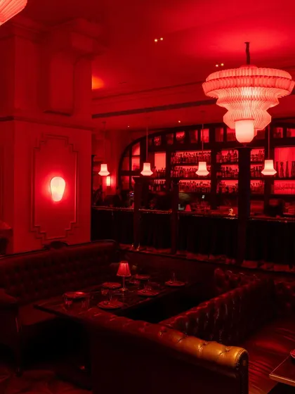 The lounge area, where the combination of chandeliers, sconces, and table lamps creates a layered and inviting lighting scheme.