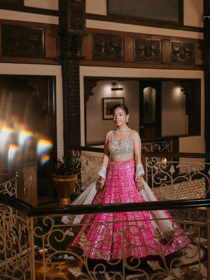 A full-length shot showing the bride's complete Sangeet look. The natural makeup allows her vibrant pink Seema Gujral lehenga to truly pop, creating a perfect balance.