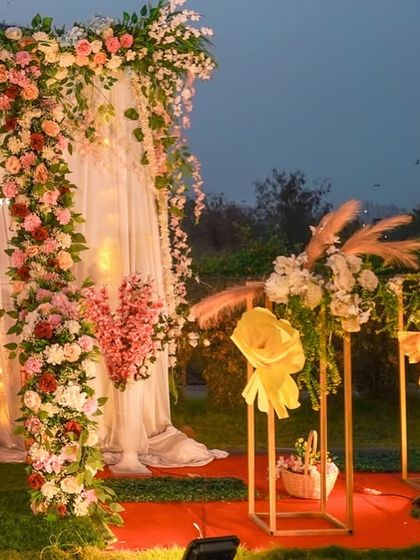 A closer look at the details of the floral arch and swing. You can see the rich mix of pink, white, and red flowers, with fairy lights woven in for a sparkling effect as evening approaches.