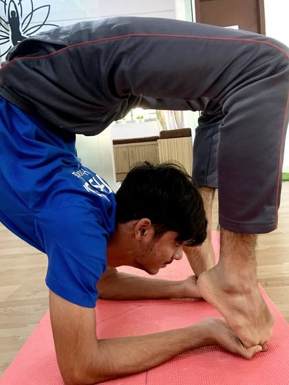 An incredible display of flexibility in this advanced forearm stand variation, where the feet touch the head.
