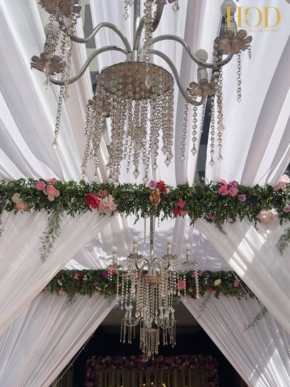 A still shot of the layered chandeliers and floral garlands, showcasing the depth and elegance of the entrance design.