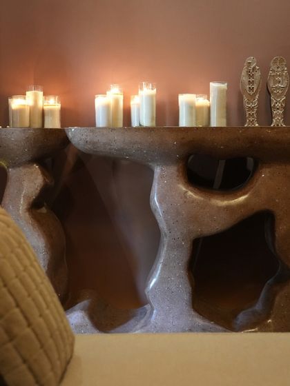 Another view of the flame-inspired Rooh Console, with candles adding to the warm, flickering ambiance. The organic cutouts and rough texture give the piece a raw, elemental feel.
