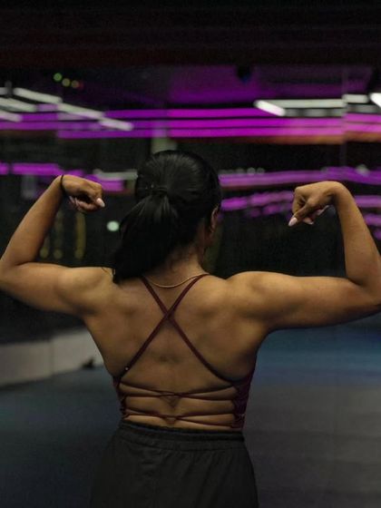 A powerful back-flex pose from my female client. This demonstrates the strength and muscle definition she built through our personalized training program.