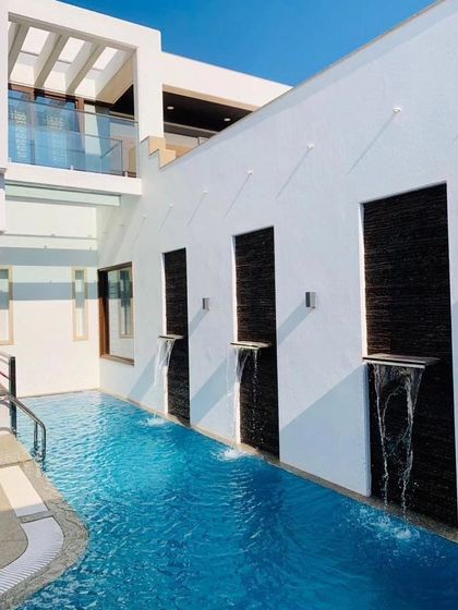 A detail of the swimming pool, which includes water spouts emerging from a textured stone wall, adding a dynamic and sensory element.