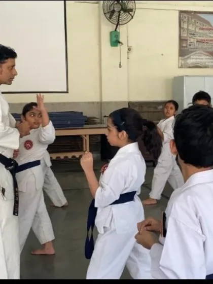 An instructor corrects a young student's blocking technique. One-on-one attention is a key part of our teaching method, helping each student refine their movements and understand the purpose behind them.