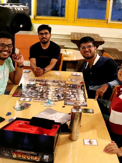 This group is deep into a game of 'Clank! In Space'. The large table provides plenty of room for complex board games, snacks, and drinks.