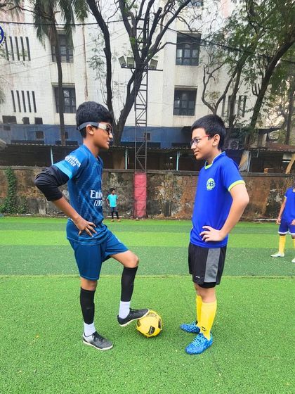 Two young footballers share a moment on the pitch. This image captures the friendship and camaraderie that develops when students train and compete together as a team.
