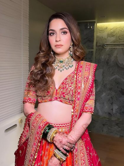 The complete look for this bride's wedding day. The combination of a traditional red and orange lehenga, classic jewelry, and my signature glowing makeup creates a look that is both timeless and breathtaking.