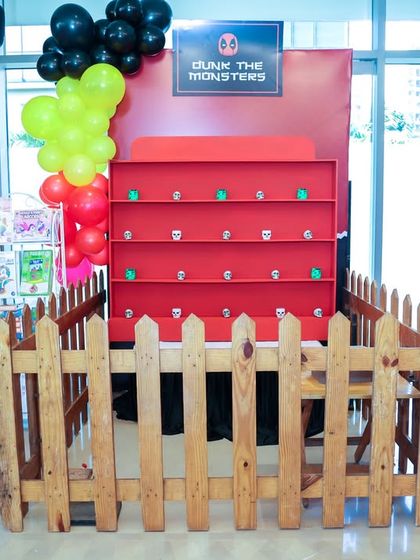 Another view of the "Dunk the Monsters" game stall, enclosed with a rustic wooden fence for a carnival-like feel.
