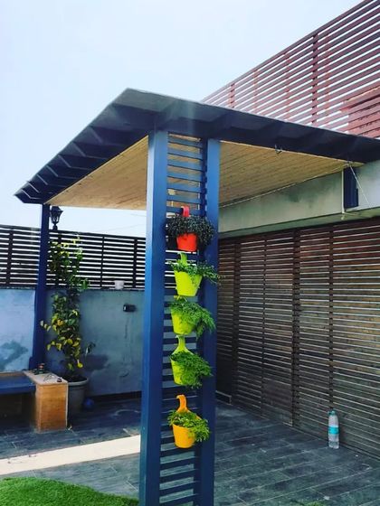 The slatted pillar of the pergola is used to hang colorful planters, adding a vertical garden element to the design.