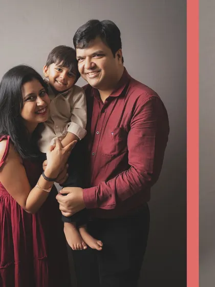 A beautiful family portrait filled with warmth and happiness. The rich maroon and burgundy tones of their outfits add a touch of elegance to this studio shot.
