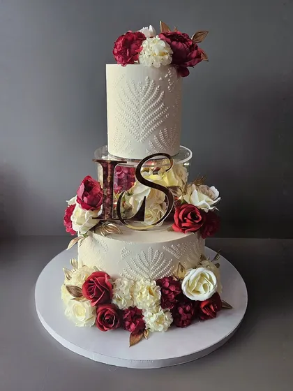 For a truly grand celebration, you need a cake to match. This three-tier wedding cake features a modern spacer, elegant stencil work, and a cascade of beautiful maroon and white sugar flowers. It’s a statement piece, designed to be as memorable as the special day itself.