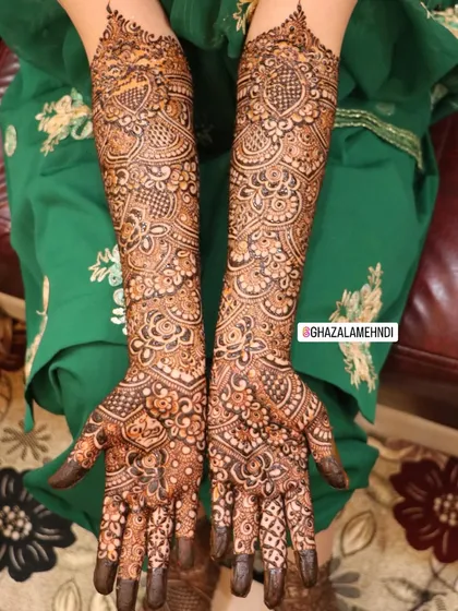 A full view of Afnan's bridal mehndi, showcasing the intricate patterns on both arms.